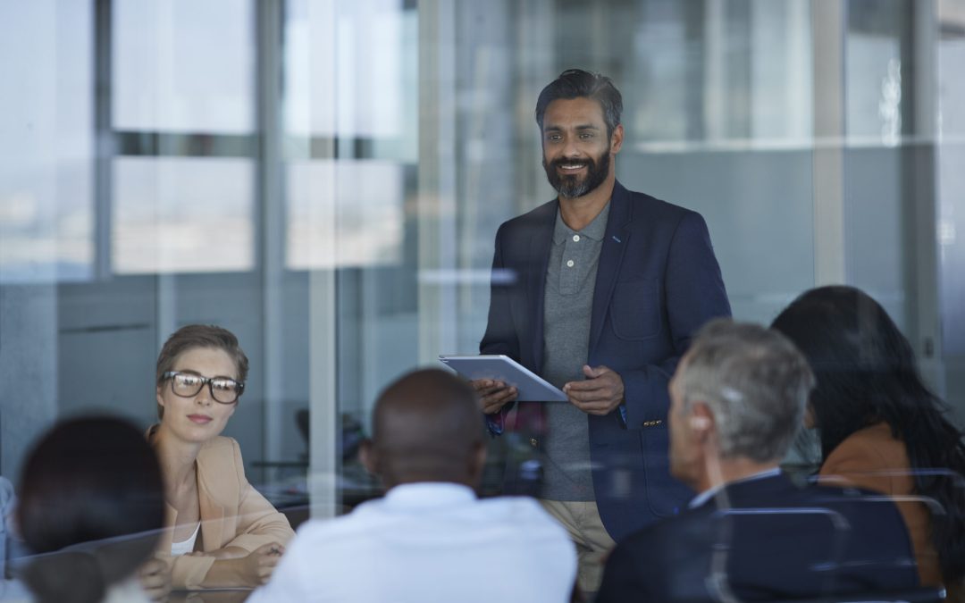 A business leader presenting to a team in a meeting room, representing how healthcare for small companies can improve employee engagement and well-being.